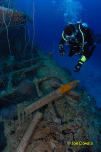 Scuba diver looks at live 5 inch shells on submarine wreck USS Apogon, Bikini Atoll