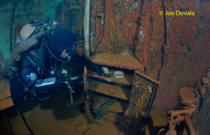 Scuba diver examines safe in dentist office on ship wreck USS Saratoga