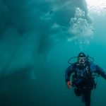 A Diver explores an iceberg (Photo by Byron Conroy)