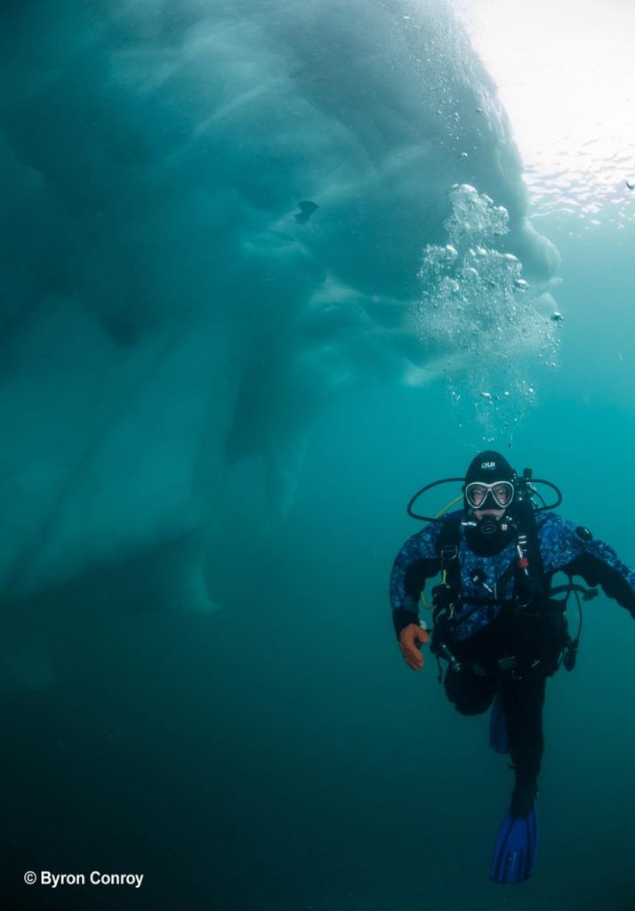 A Diver explores an iceberg (Photo by Byron Conroy)